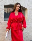 Satin kimono with a belt, made from polyester, viscose and elastane, with smooth and luxurious texture, placed on bed.