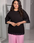 Жена носи Whiteа Lace T-shirt от cotton и elastane, с ръчно шит дизайн и деликатни дантеlinenи детайли.