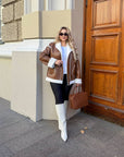 Short faux leather coat, waist-length, in black, with long sleeves and a modern design.