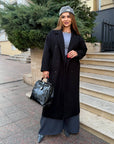 Long faux-cashmere coat with polyester, viscose and wool, lying on wooden bench, in gentle natural tones.