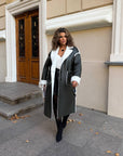 Long faux leather coat with a stylish design, a model wearing a black coat with long sleeves.