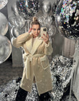 Long mixed-fabric coat in polyester and spandex, shown on a model, with long sleeves and a modern cut.