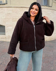 Short faux fur coat in polyester and acrylic, with long sleeves and a modern design, product photo in white.