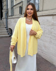 Cropped cardigan with a belt made from cotton and polyester, model from Composition, model with cut and belt at the front.